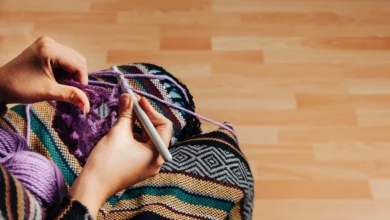 Mãos trabalhando em um projeto de crochê para tapete com fio roxo em um ambiente aconchegante.