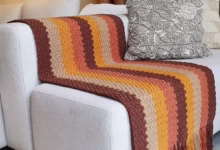 Manta de crochê com listras e franjas decorando sofá branco