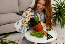 Mulher sorridente plantando em casa com ferramentas de jardinagem e vaso de planta em um ambiente aconchegante.