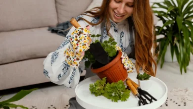 Mulher sorridente plantando em casa com ferramentas de jardinagem e vaso de planta em um ambiente aconchegante.