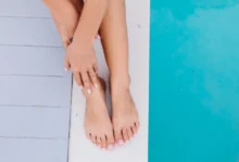 Pés de mulher com esmalte francesinha, delicado e elegante, à beira de uma piscina.