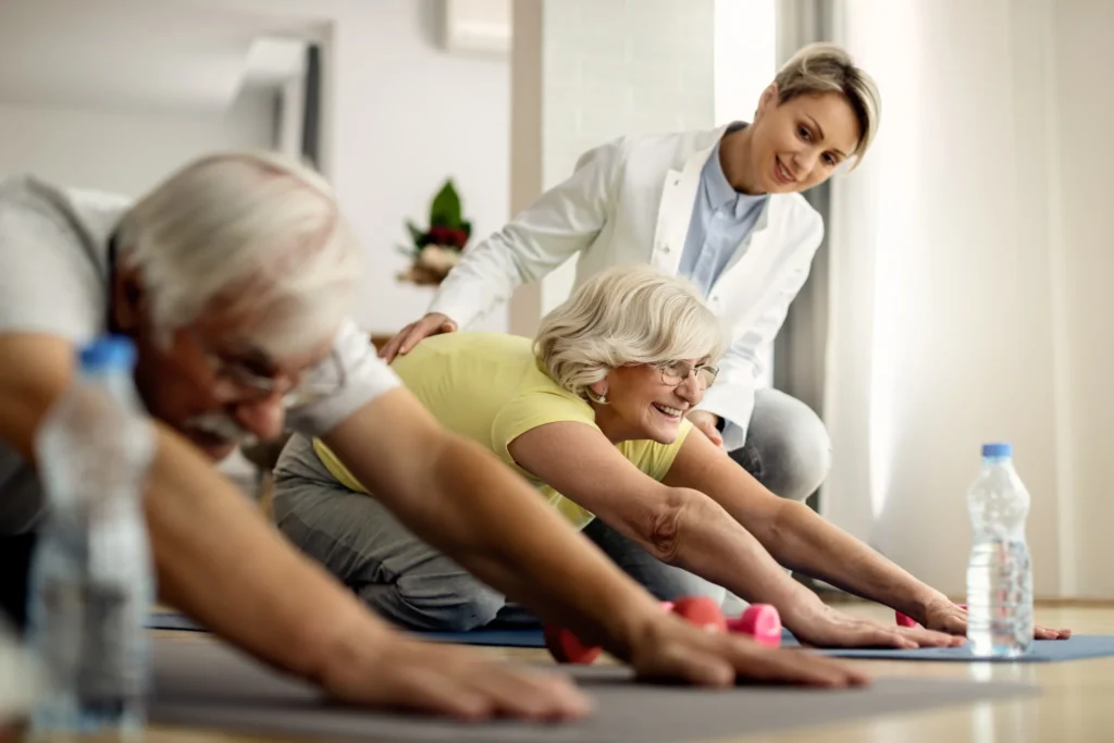 Idosos fazendo alongamento com a ajuda de um fisioterapeuta, praticando exercícios para a lombar.