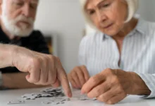 Casal de idosos fazendo um exercício cognitivo, montando um quebra-cabeça, atividade recomendada para manter a mente afiada.