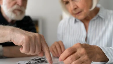 Casal de idosos fazendo um exercício cognitivo, montando um quebra-cabeça, atividade recomendada para manter a mente afiada.