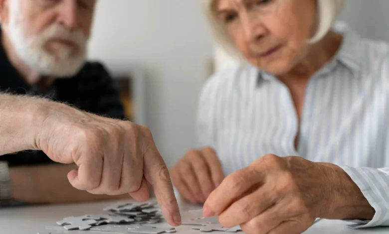 Casal de idosos fazendo um exercício cognitivo, montando um quebra-cabeça, atividade recomendada para manter a mente afiada.