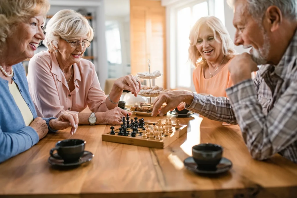 Grupo de amigos jogando xadrez e socializando durante um café, promovendo habilidades cognitivas e sociais.
