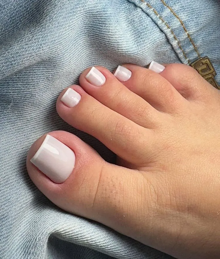Francesinha nos pés com esmalte branco nas pontas Imagem de unhas dos pés com francesinha, mostrando o efeito delicado.