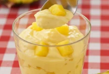 Gelado de abacaxi com creme em copo transparente com pedaços de abacaxi fresco