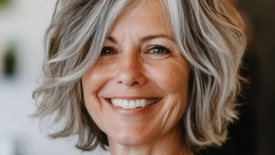 Mulher de cabelo grisalho com mechas platinadas, sorrindo e exibindo um visual elegante e moderno.