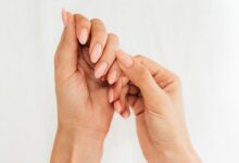 Mãos femininas com unhas alongadas, esmaltadas e bem cuidadas em tom nude