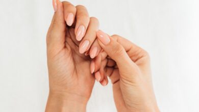Mãos femininas com unhas alongadas, esmaltadas e bem cuidadas em tom nude