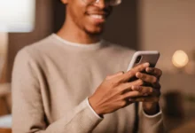 Homem sorridente usando celular para enviar mensagens no WhatsApp.