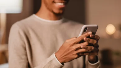 Homem sorridente usando celular para enviar mensagens no WhatsApp.