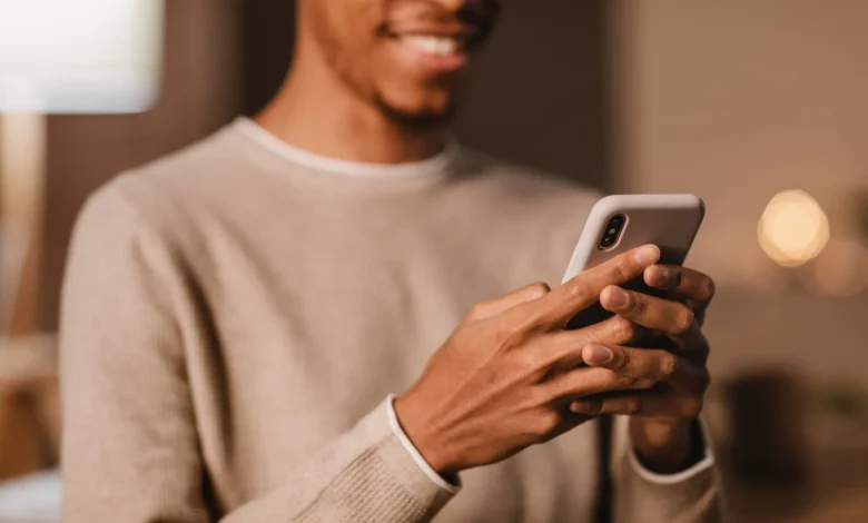 Homem sorridente usando celular para enviar mensagens no WhatsApp.