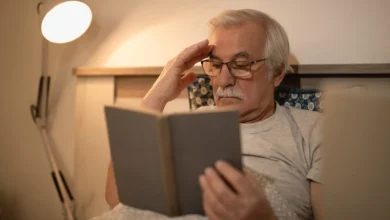 Homem idoso lendo um livro à noite na cama, focado em melhorar a memória com dicas importantes para a terceira idade.