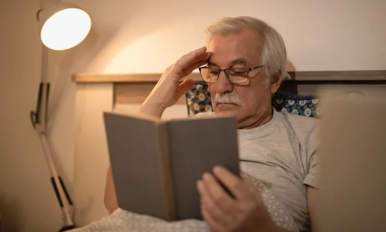 Homem idoso lendo um livro à noite na cama, focado em melhorar a memória com dicas importantes para a terceira idade.