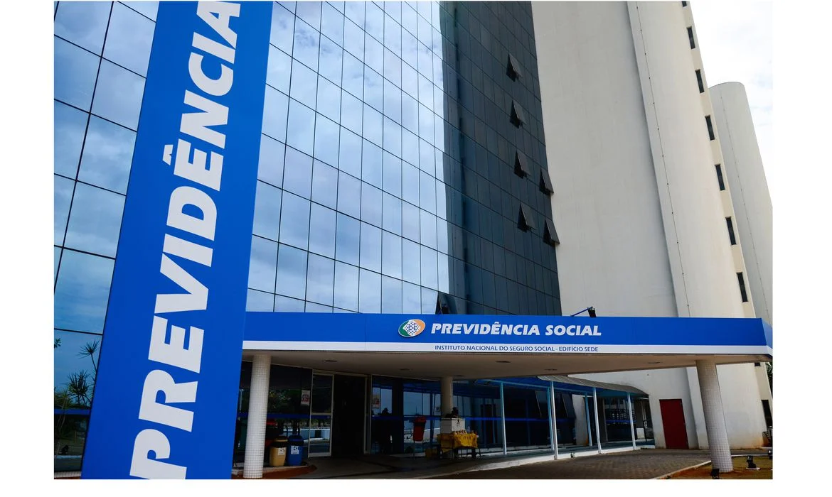 Fachada do prédio do INSS, com a inscrição Previdência Social' em destaque na entrada do edifício.