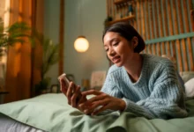 Mulher deitada na cama usando o celular com expressão tranquila