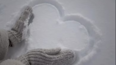 Desenho de um coração na neve feito com as mãos, simbolizando carinho e afeto em um dia frio
