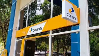 Fachada da agência dos Correios, com o logotipo visível e elementos de branding em azul e amarelo.