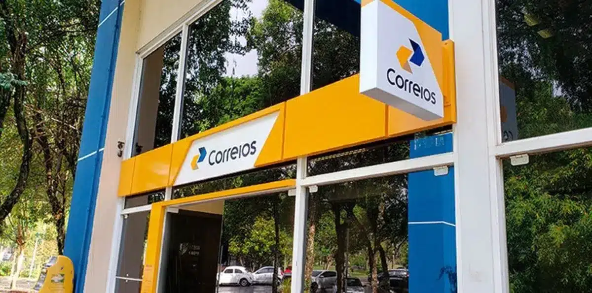 Fachada da agência dos Correios, com o logotipo visível e elementos de branding em azul e amarelo.