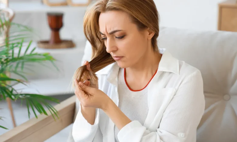 Mulher analisando pontas ressecadas em cabelo fino e danificado