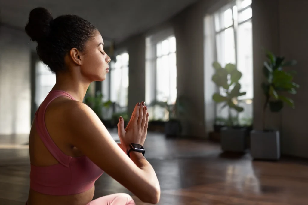 Mulher praticando mindfulness, meditando em um ambiente tranquilo com luz natural.