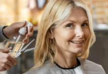 Mulher madura sorrindo ao se preparar para cortar o cabelo no salão.