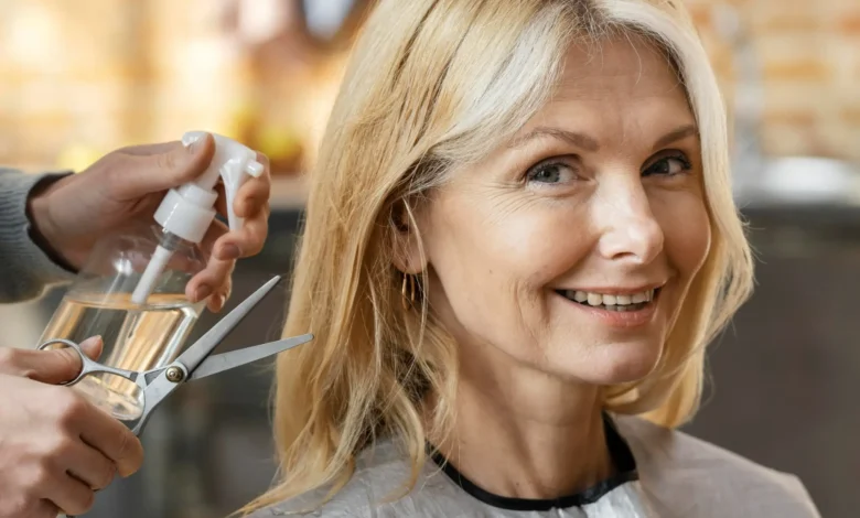 Mulher madura sorrindo ao se preparar para cortar o cabelo no salão.