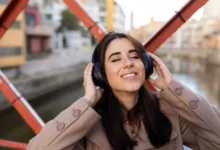 Mulher sorridente ouvindo música com fones de ouvido, relaxando em ambiente ao ar livre