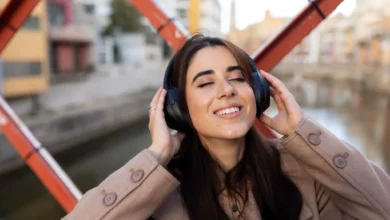 Mulher sorridente ouvindo música com fones de ouvido, relaxando em ambiente ao ar livre