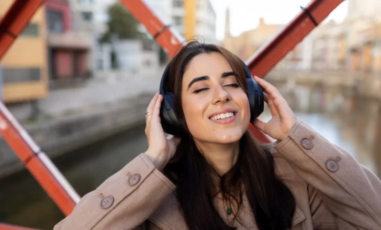 Mulher sorridente ouvindo música com fones de ouvido, relaxando em ambiente ao ar livre