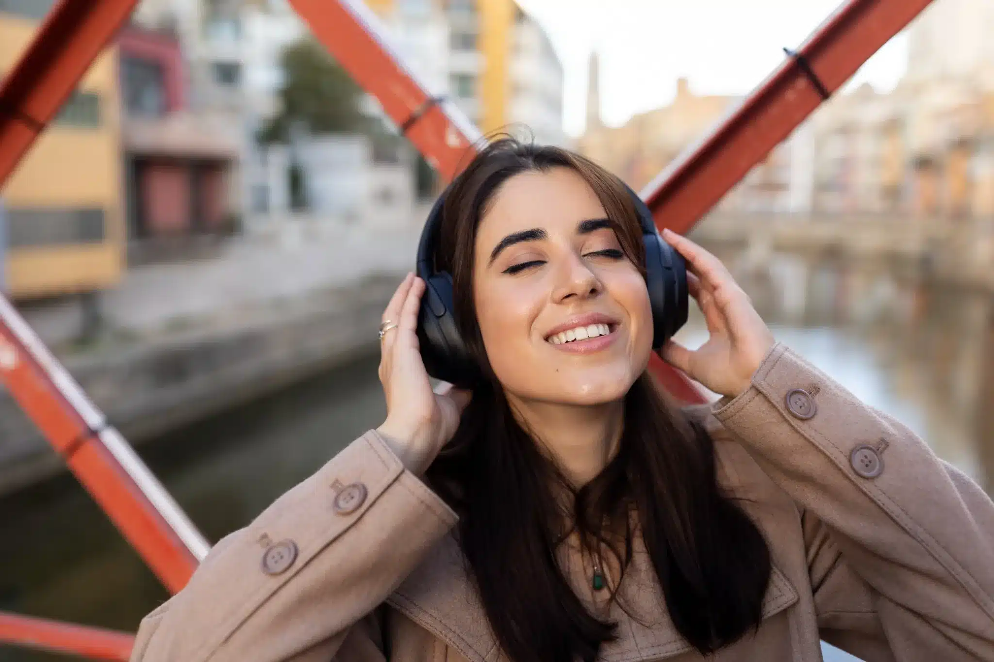 Mulher sorridente ouvindo música com fones de ouvido, relaxando em ambiente ao ar livre