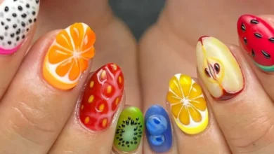 Unhas decoradas com frutas, mostrando nail art criativa com laranja, limão, kiwi, morango, maçã e melancia.