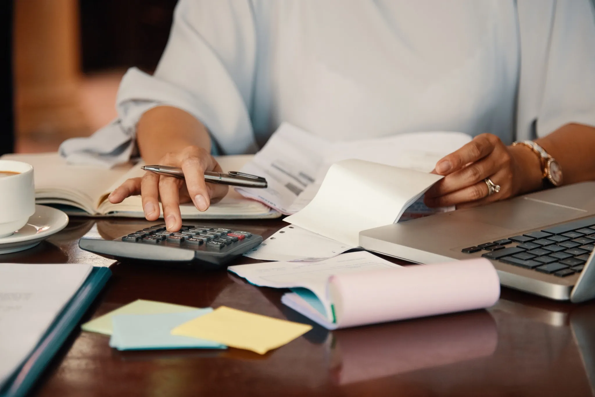 Pessoa organizando contas e finanças com calculadora e notebook.