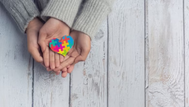 Representação simbólica de apoio aos pais de pessoas com autismo ou deficiência, com as mãos de duas pessoas segurando um coração de quebra-cabeça colorido.