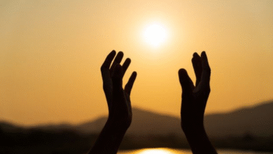 Mãos abertas ao sol, simbolizando a recepção de bênçãos para um mês de julho repleto de paz e esperança.