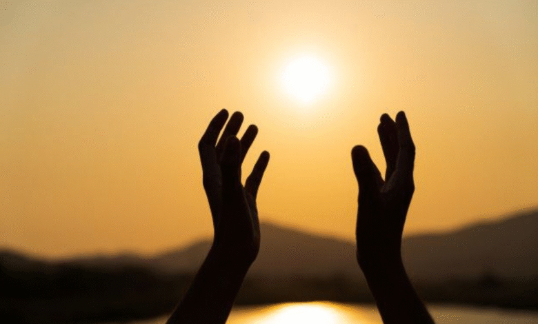Mãos abertas ao sol, simbolizando a recepção de bênçãos para um mês de julho repleto de paz e esperança.