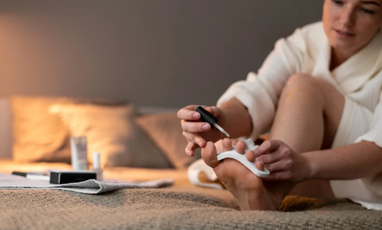 Mulher fazendo a pedicure em casa, aplicando esmalte nos pés com cuidado e conforto.