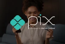 Mulher sorrindo enquanto segura um smartphone e um cartão de crédito, destacando o uso do PIX como solução de pagamento.