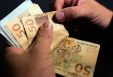 Pessoas contando notas de R$ 50, simbolizando o pagamento dos salários.