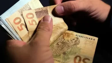 Pessoas contando notas de R$ 50, simbolizando o pagamento dos salários.
