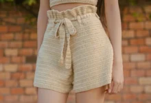 Shorts de crochê bege com cintura alta e detalhe em laço na frente.
