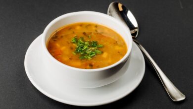 Caldo de mocotó servido em tigela branca com ervas frescas por cima