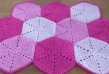 Tapete de crochê hexagonal em tons de rosa e lilás, formando um padrão geométrico