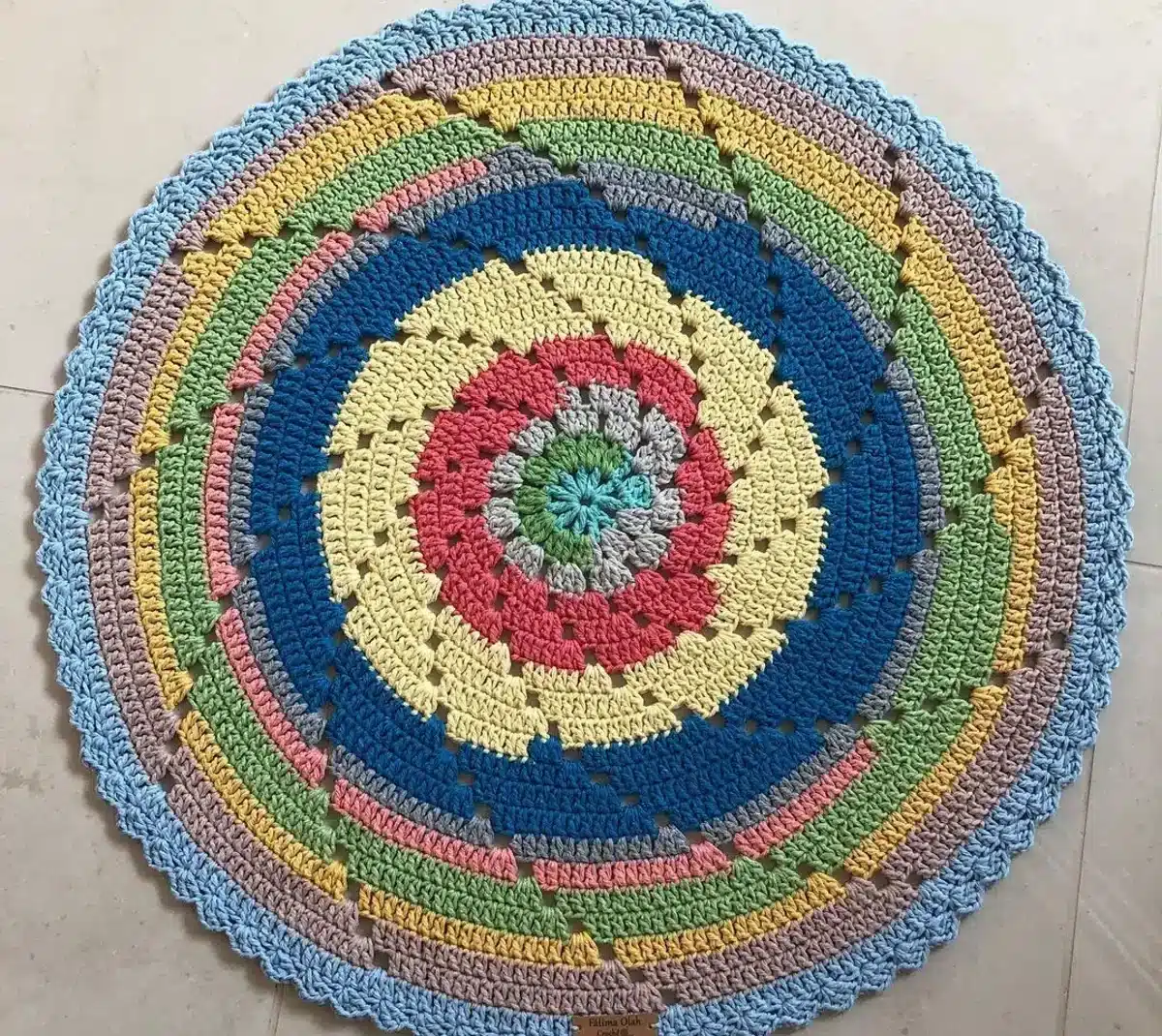 Tapete redondo de crochê colorido com design espiral, feito com fios de algodão e pontos delicados, ideal para decoração aconchegante.