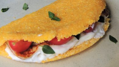 Tapioca de cuscuz recheada com frango, tomate, queijo cremoso e folhas de manjericão