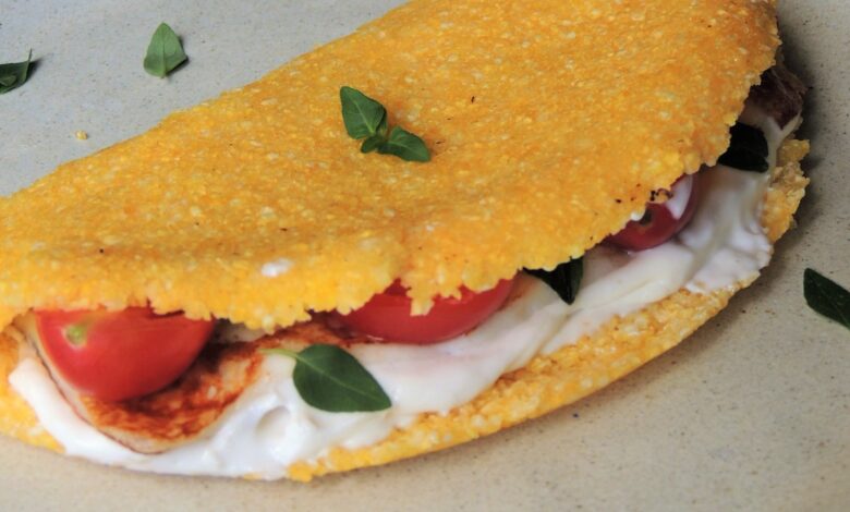 Tapioca de cuscuz recheada com frango, tomate, queijo cremoso e folhas de manjericão