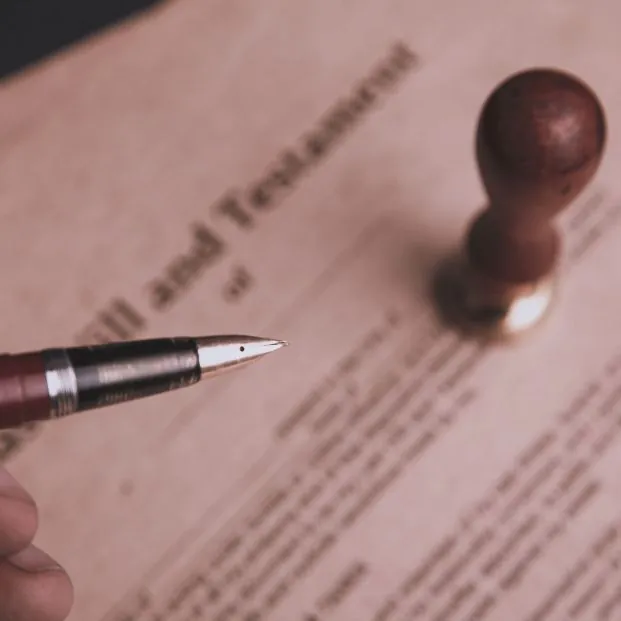 Caneta e carimbo sobre um testamento, simbolizando a formalização de um planejamento sucessório.