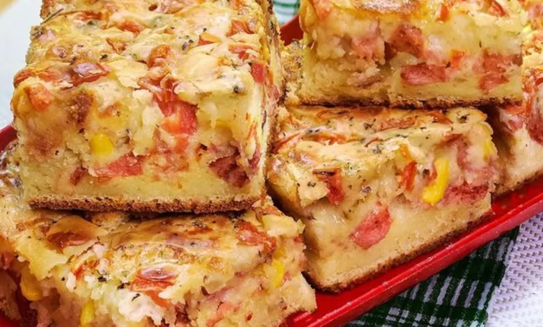 Fatias de torta salgada com queijo derretido, tomate, milho e uma crosta dourada sobre um prato vermelho.